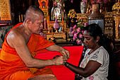 Bangkok Wat Arun - Buddist monk inside the Ubosot gives the sacred thread (sai sin). 